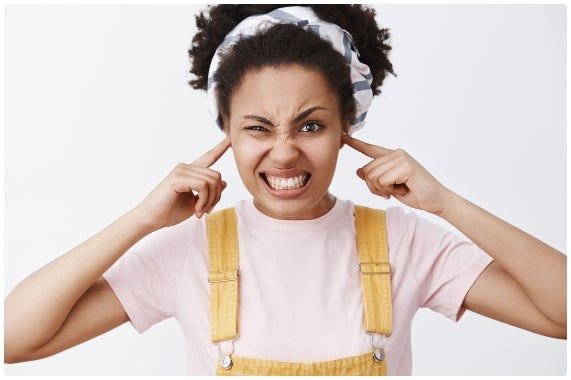 Angry, annoyed African American woman plugging her ears with her fingers