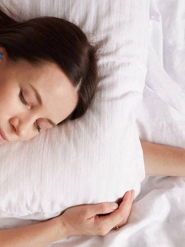 Young brunette woman sleeping comfortably while wearing beeswax earplugs